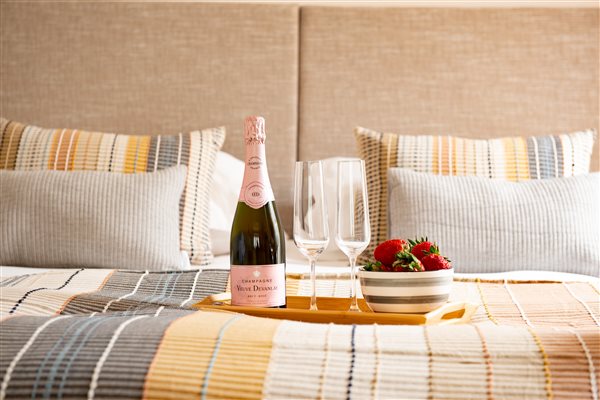 Bed with cushions and throw with tray of Champaign and strawberries.